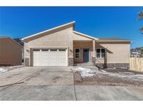 Charming stucco home featuring a two-car garage, covered entry, and well-manicured landscaping at 93 Greeley Blvd, Palmer Lake, CO 80133
