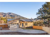 Charming single-Gathering home with a two-car garage and inviting blue front door, surrounded by lush greenery and mountain views at 93 Greeley Blvd, Palmer Lake, CO 80133