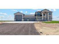 Stunning two-story home featuring a three-car garage and stone detailing under a blue sky at 2990 S Juliet Ct, Strasburg, CO 80136