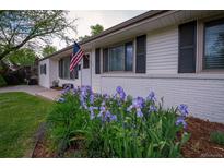 Charming home exterior with a well-maintained lawn and a garden with purple flowers in the front yard at 4425 E Harvard Ave, Denver, CO 80222
