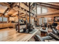 Bright, open living area with wood beams, hardwood floors, and wood burning stove at 1673 Sinton Rd, Evergreen, CO 80439