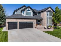 Beautiful home featuring a brick facade, black garage doors and inviting front porch with seating at 7067 Gray Fox Ct, Highlands Ranch, CO 80130