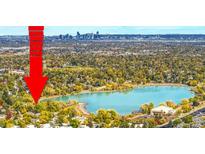 Stunning aerial view with a large turquoise lake surrounded by lush trees and the Denver skyline in the distance at 1712 S Kline Way, Lakewood, CO 80232