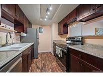Well-lit kitchen with stainless steel appliances, granite countertops, and dark wood cabinets at 13393 E Asbury Dr # 103, Aurora, CO 80014