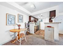 Eat-in kitchen featuring stainless steel appliances, dark wood cabinets, and a cozy dining area with natural light at 13393 E Asbury Dr # 103, Aurora, CO 80014