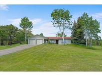 Charming ranch-style home with a lush lawn, mature trees, and a two-car garage at 8427 S Custer Ln, Evergreen, CO 80439