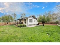 Expansive backyard featuring lush green grass, mature trees, and a charming covered porch, perfect for outdoor relaxation at 5326 Lowell Blvd, Denver, CO 80221