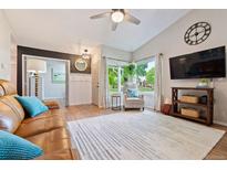 Inviting living room featuring a leather sofa, ceiling fan, and large windows with a view of the outdoors at 7 Shetland Ct, Highlands Ranch, CO 80130