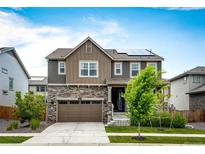Two-story home with stone accents, a two-car garage, solar panels, and a well-maintained front yard at 985 S Elk Way, Aurora, CO 80018