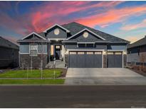 Charming two-story home with a three-car garage and beautiful stone accents at sunset at 9035 S Shawnee Ct, Aurora, CO 80016