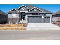 Charming two-story home showcasing a three car garage and stone accents at 9035 S Shawnee Ct, Aurora, CO 80016