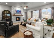 Bright living room featuring a stone fireplace, ceiling fan and large windows for an abundance of natural light at 9035 S Shawnee Ct, Aurora, CO 80016