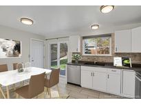 Bright kitchen featuring white cabinets, tile backsplash, stainless steel appliances, and sliding patio door at 8001 S Estes St, Littleton, CO 80128