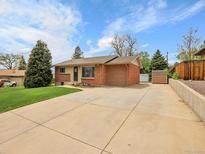 Charming brick and siding home featuring a well-maintained lawn, wide driveway and mature trees under a bright sky at 2797 S Newton Way, Denver, CO 80236
