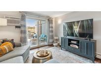 Bright living room with a sliding glass door to a private patio, and a modern entertainment center at 2835 S Monaco Pkwy # 1-103, Denver, CO 80222