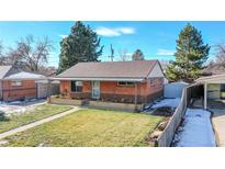 Charming brick home featuring a well-maintained lawn, covered porch, and convenient carport, perfect for curb appeal at 7081 Warren Dr, Denver, CO 80221