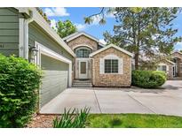 Charming home featuring stone accents, a well-manicured lawn, and an attached two-car garage at 7400 W Grant Ranch Blvd # 52, Littleton, CO 80123