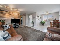 Spacious living room featuring a wooden accent wall, plush rug, and lots of natural light at 8798 Chase Dr # 4, Arvada, CO 80003