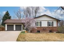 Charming home featuring a two-car garage, brick accents, and blossoming tree in the front yard at 6847 S Hill St, Littleton, CO 80120