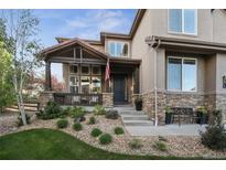 Inviting front porch with stone accents, dark wood, and manicured landscaping at 17490 W 67Th Ave, Arvada, CO 80007