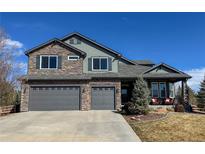 Beautiful two-story home featuring stone accents, three-car garage, and covered front porch at 5893 Lasso Pl, Parker, CO 80134