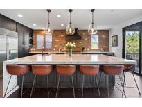 Modern kitchen boasts a marble island with barstool seating, brick backsplash, and pendant lighting at 7963 S Valleyhead Way, Aurora, CO 80016