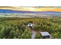 Expansive aerial view of a secluded home surrounded by lush forest and rolling hills at sunset at 5090 S Perry Park, Sedalia, CO 80135