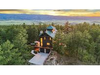 Stunning exterior view of a wood-sided home nestled amongst trees with a mountain view at 5090 S Perry Park, Sedalia, CO 80135