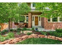 Charming brick home features a welcoming front porch with chairs and beautifully landscaped front yard at 16177 E Prentice Pl, Centennial, CO 80015