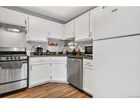 Well-lit kitchen featuring stainless steel appliances, white cabinetry, and wood-look flooring at 63 S Sable Blvd # 16, Aurora, CO 80012