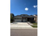 Charming home featuring a stone facade, three-car garage, a small front porch, and well-manicured landscaping at 8163 S Valleyhead Way, Aurora, CO 80016