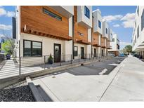 Modern townhomes with wood and white exteriors line a concrete walkway with wrought iron railing at 3414 W 18Th Ave, Denver, CO 80204