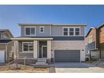 Two-story home with gray and white brick exterior, attached garage, and small front porch at 783 Sunflower Dr, Brighton, CO 80601