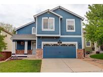 Charming two-story home featuring a blue exterior, landscaped yard, and a two-car garage at 10364 Ravenswood Way, Highlands Ranch, CO 80130