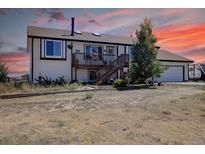 Charming two-story home featuring a spacious deck, black trim, and an attached two car garage at 43400 Somerset Ct, Elizabeth, CO 80107