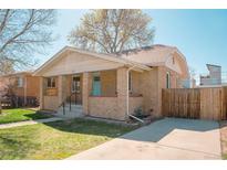 Charming brick bungalow with a covered front porch, landscaped yard, and a blue front door at 1357 Xavier St, Denver, CO 80204