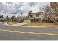 Charming two-story home with a well-maintained lawn and attached two car garage on a cloudy day at 8155 Everett E St, Arvada, CO 80005