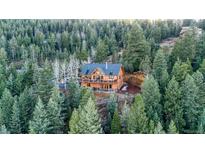 Stunning log home surrounded by lush evergreens, featuring a large deck and a private, wooded setting at 1055 Saddleback Dr, Evergreen, CO 80439