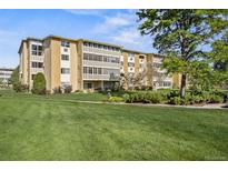 Low-rise condominium with manicured green lawn, lush shrubs, and mature trees at 610 S Alton Way # 7C, Denver, CO 80247