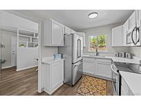 Bright kitchen featuring stainless steel appliances, white cabinetry, and wood-look floors at 957 Newton St, Denver, CO 80204