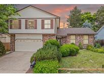 Charming brick home with a two-car garage, well-maintained lawn, and mature landscaping at 4677 S Wolff St, Denver, CO 80236