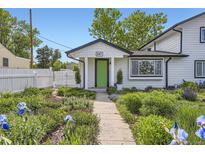 Charming home with a landscaped front yard, white picket fence, and a bright green front door at 947 S Yates St, Denver, CO 80219
