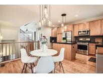 Bright kitchen and dining area with hardwood floors, stainless steel appliances, and modern lighting fixtures at 453 S Quay Street, Lakewood, CO 80226