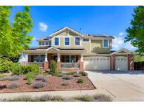 Inviting two-story home featuring a charming front porch, lush landscaping, and solar panels on the roof at 21395 E Greenwood Pl, Aurora, CO 80013