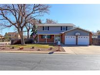 Two story home featuring a large front yard with mature trees and two car garage with basketball hoop at 9202 W Virginia Pl, Lakewood, CO 80226