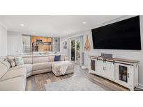 Bright living room featuring a sectional sofa, decorative cabinets, and sliding glass doors at 92 Helena Cir, Littleton, CO 80124