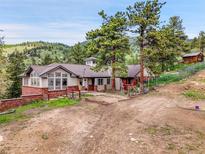 Stunning multi-level home nestled among mature trees with mountain views and a wraparound brick-lined patio at 6094 Pyrenees Trl, Golden, CO 80403