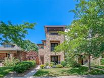 Stunning multi-story home featuring a stone facade, balcony, and lush landscaping at 2741 Java Ct, Denver, CO 80211