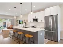 Modern kitchen boasts stainless appliances, white cabinets, island with seating, and stylish pendant lighting at 3103 S Cherokee St, Englewood, CO 80110