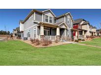 Charming gray two-story home with stone accents, covered porch, and well-manicured lawn on a sunny day at 17851 E 103Rd Ave, Commerce City, CO 80022
